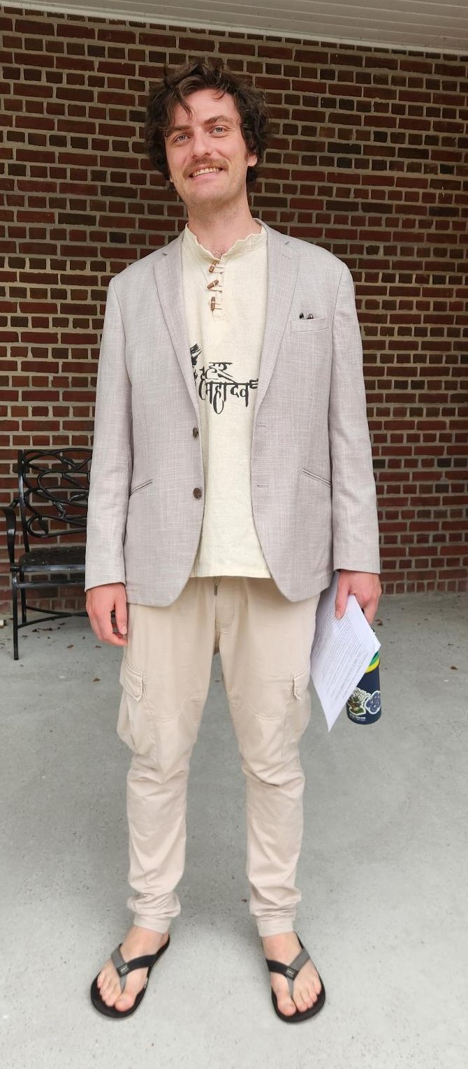 Corey Boiko, founder of Apt Logic Solutions, standing on a brick porch in a linen blazer