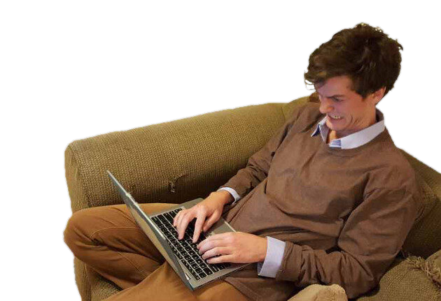 Corey Boiko working on a laptop from a couch